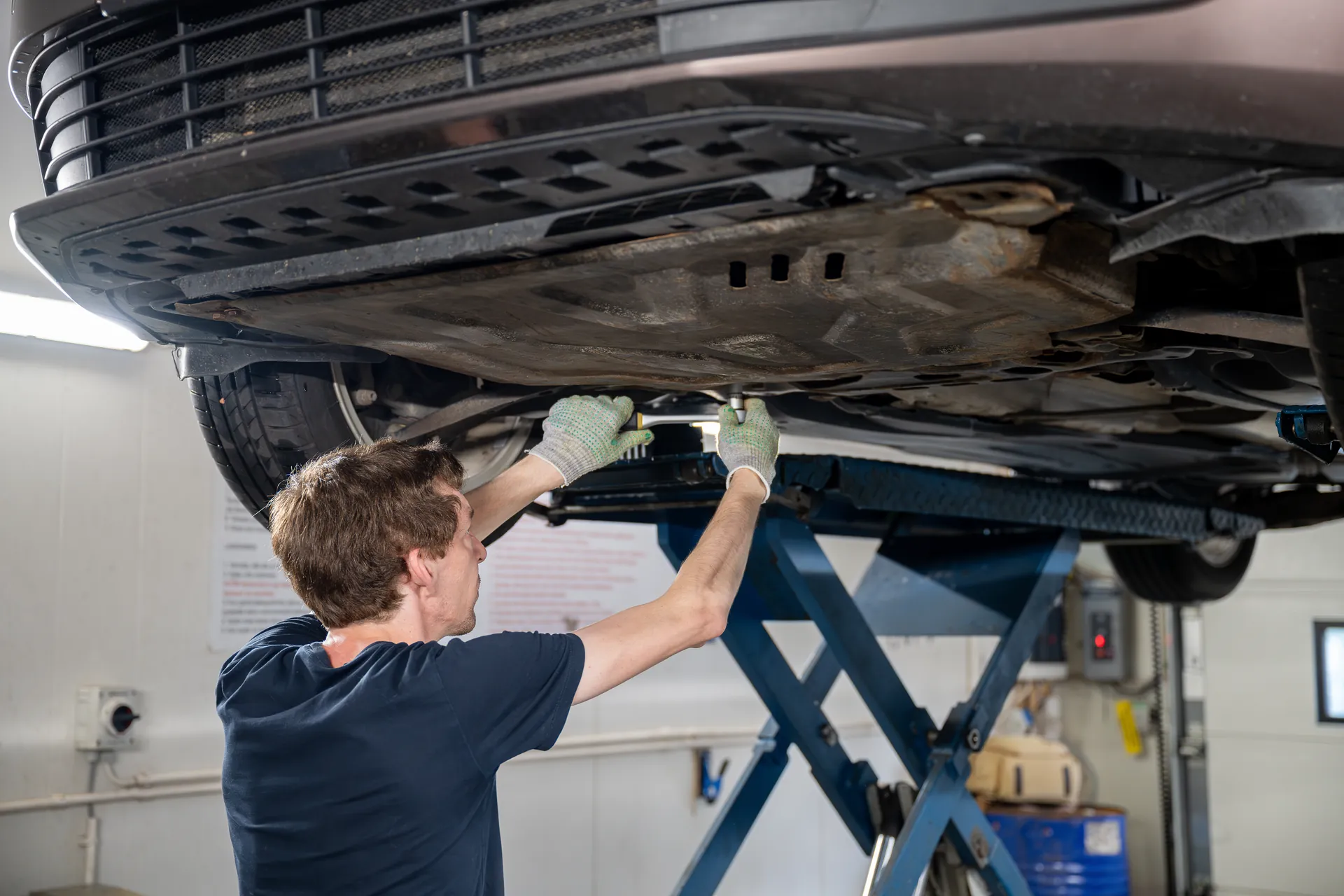Mechanic working under the front of a lifted car near the transmission