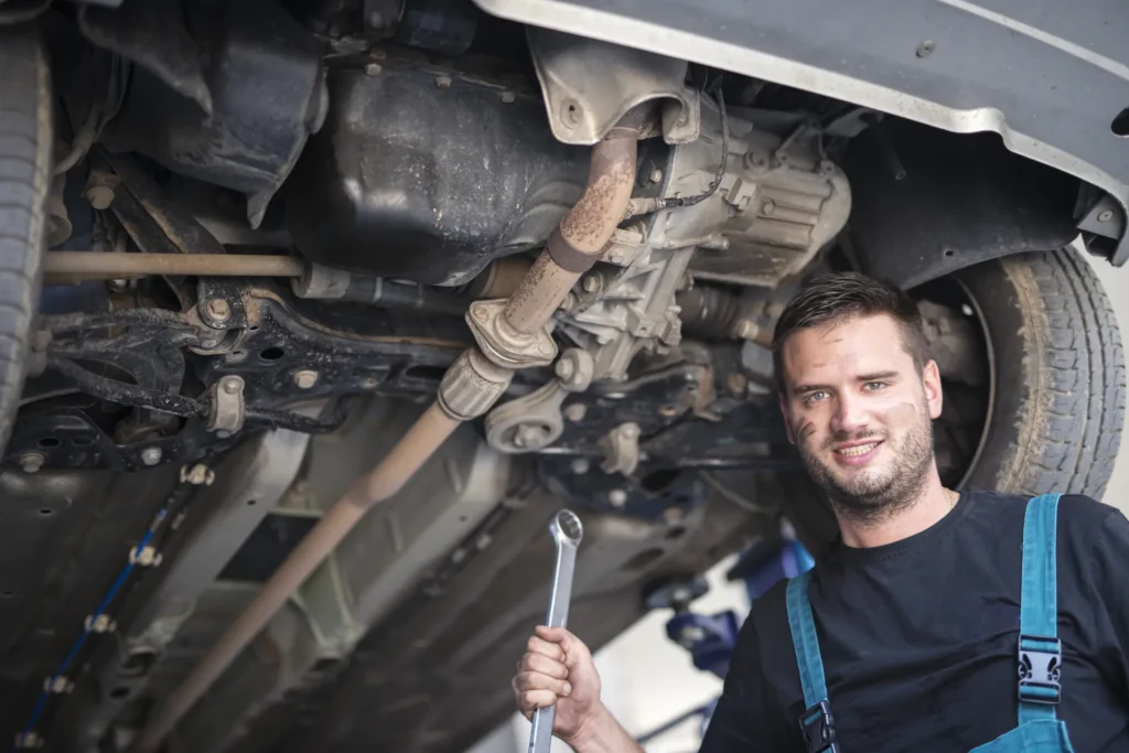 Mechanic under a vehicle in a repair shop checking the transmission for warning signs