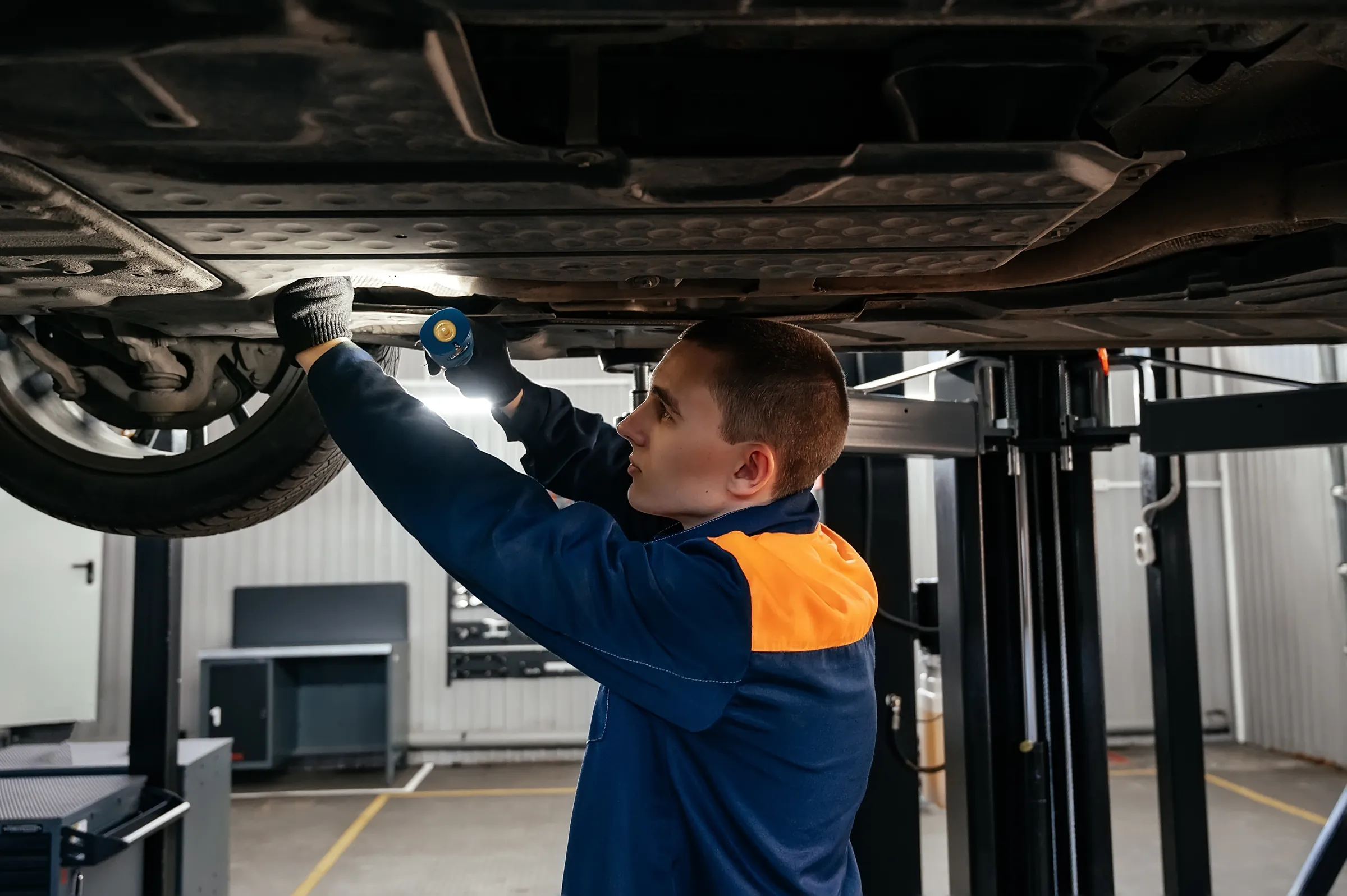 Technician working underneath a vehicle near the transmission at a Woodbridge shop