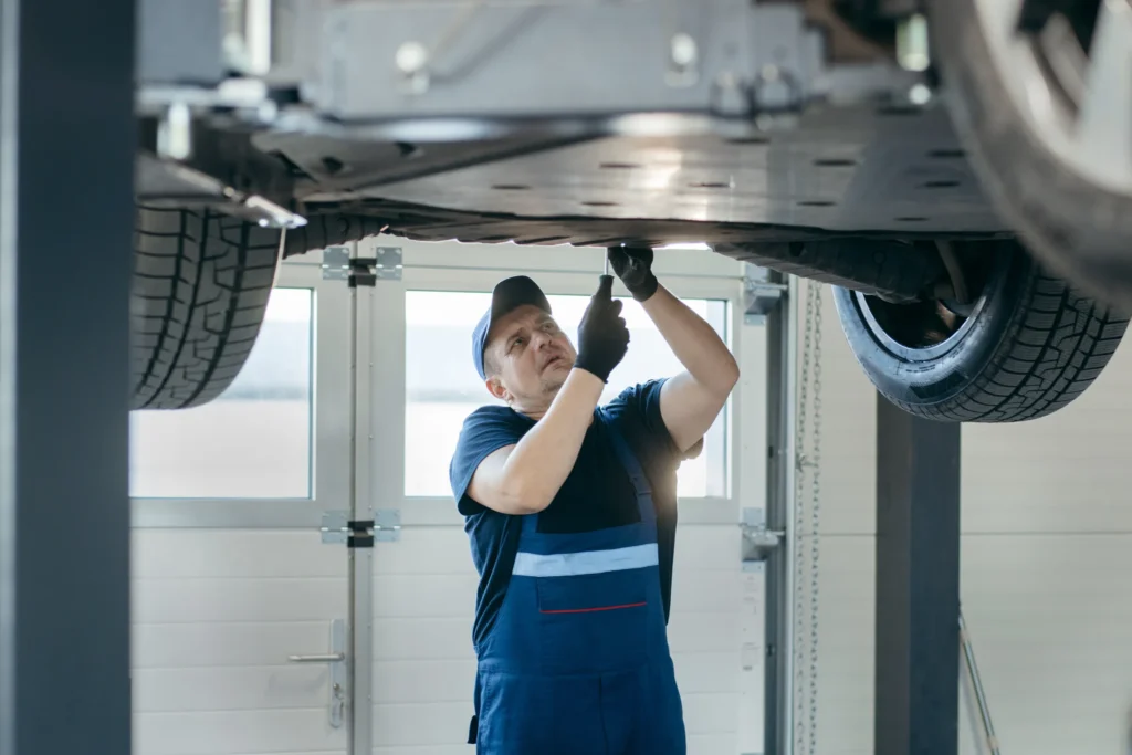 Technician servicing a vehicle on a lift for transmission fluid service